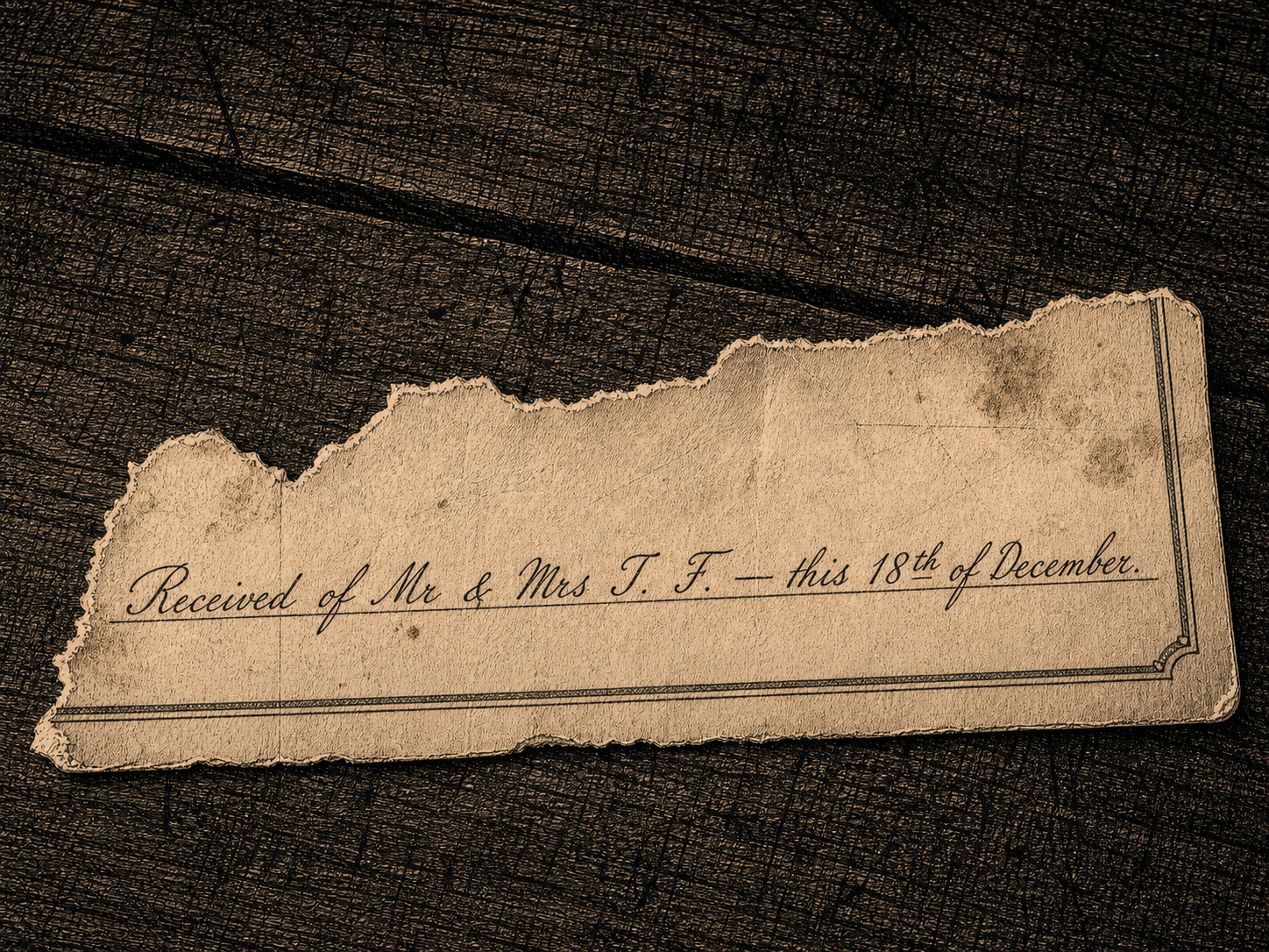 A torn corner of a printed receipt-stub on a dark wooden surface; the office name and the matter of it are torn away, leaving only a clerk's handwritten line reading 'Received of Mr & Mrs T. F. — this 18th of December.'